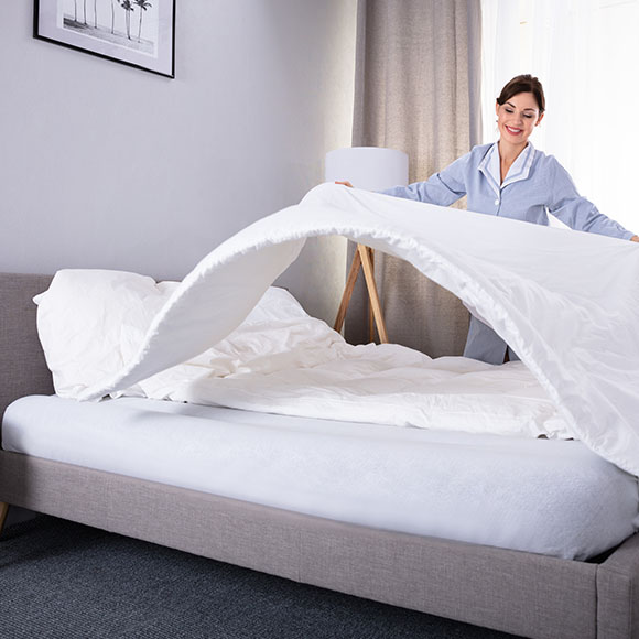 Coton Textilreinigung - Reinigung Bettwäsche - Zimmermädchen beim Bettmachen mit frischer Bettwäsche
